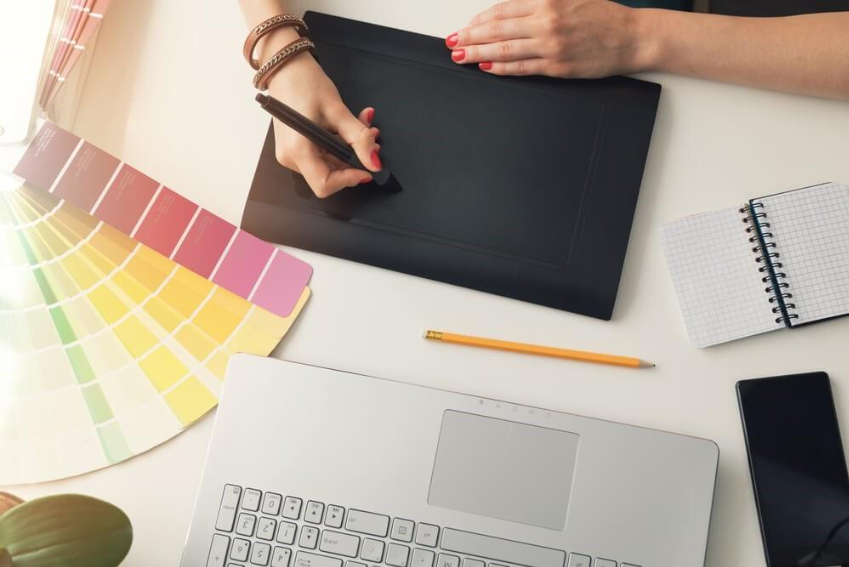 Ilustração de designer trabalhando com mesa digitalizadora e paleta de cores, representando a aplicação prática dos princípios de Gestalt no design