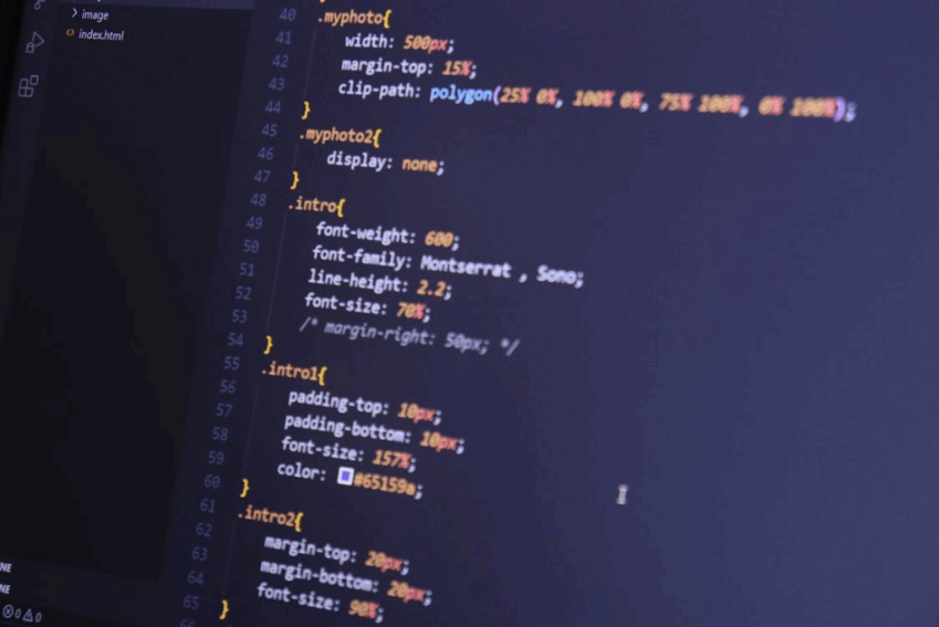 Um close-up de um monitor de computador exibindo um arquivo de código CSS em um editor com tema escuro.  