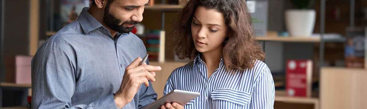 um homem e uma mulher conversando com um tablet em mãos, representando a mentoria organizacional