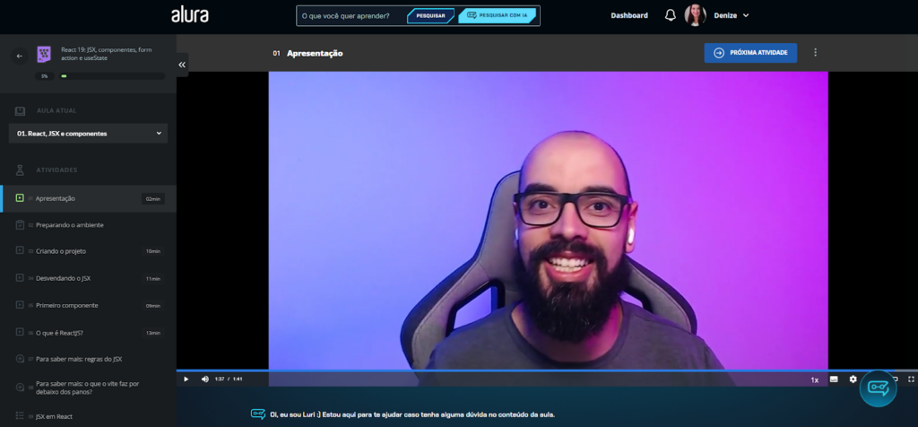 Tela de aula da plataforma Alura, exibindo um vídeo de apresentação do curso "React 19: JSX, componentes, form action e useState". À esquerda, um menu com a lista de aulas e duração de cada uma. No centro, o vídeo mostra um instrutor sorrindo, com fundo em degrade roxo e azul. No topo, botões de navegação e pesquisa, além do perfil do usuário logado. Na parte inferior, o assistente virtual Luri oferece ajuda.