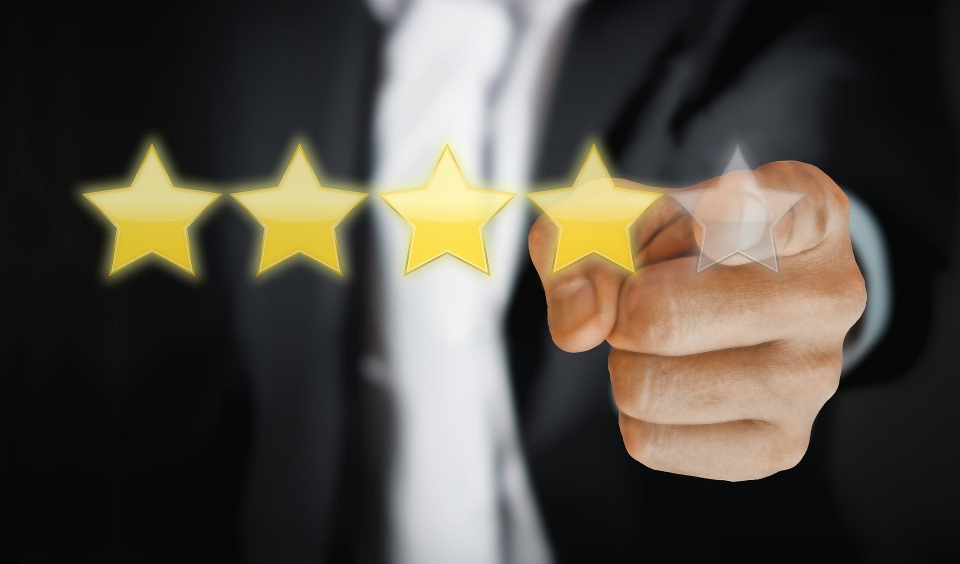Um homem de terno desfocado apontando para 5 estrelas.